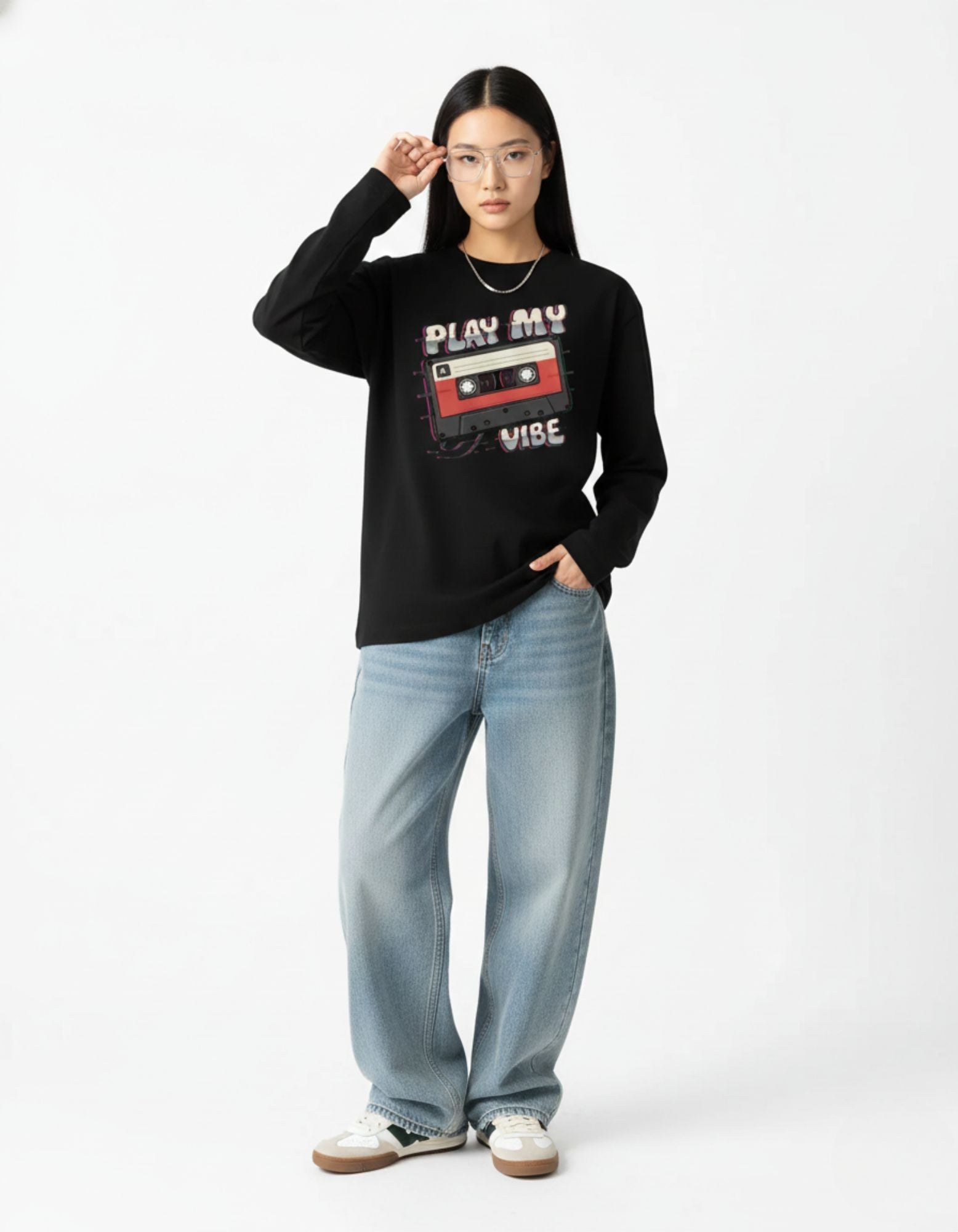 Person wearing a black sweatshirt with a graphic design and light blue jeans on a white background