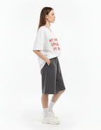 Women's oversized quote graphic t-shirt in white by GENZs Fashion, paired with grey baggy sweat-shorts.