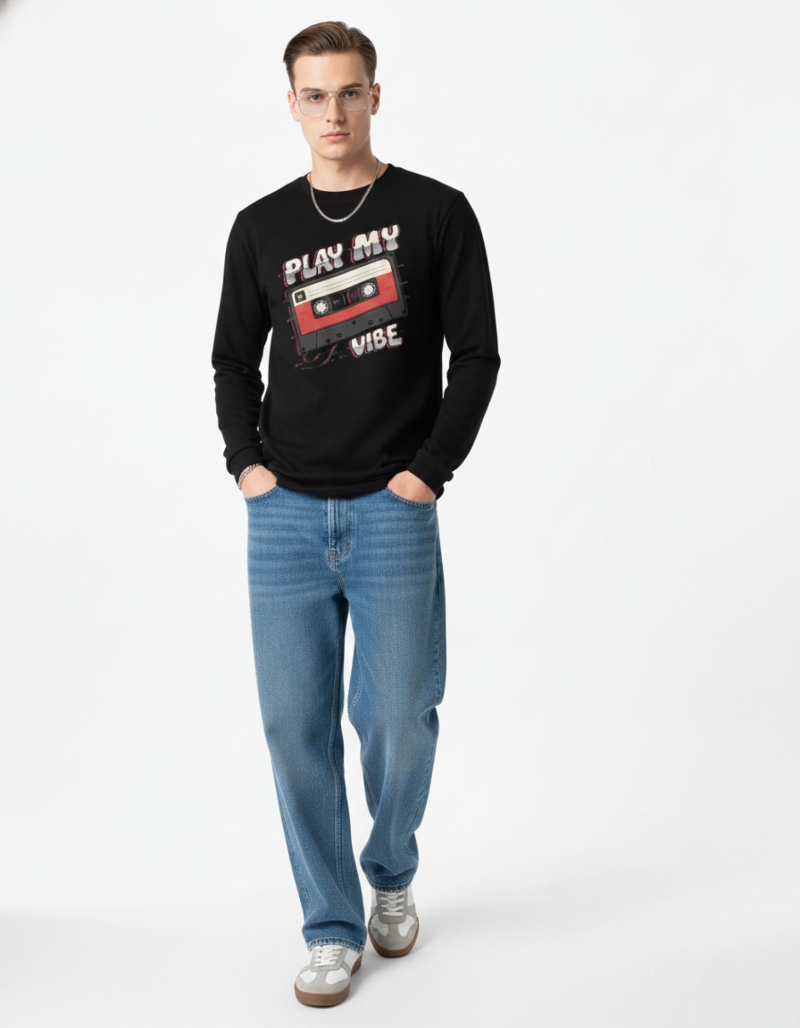 Man wearing a black sweatshirt with a graphic design and blue jeans on a white background