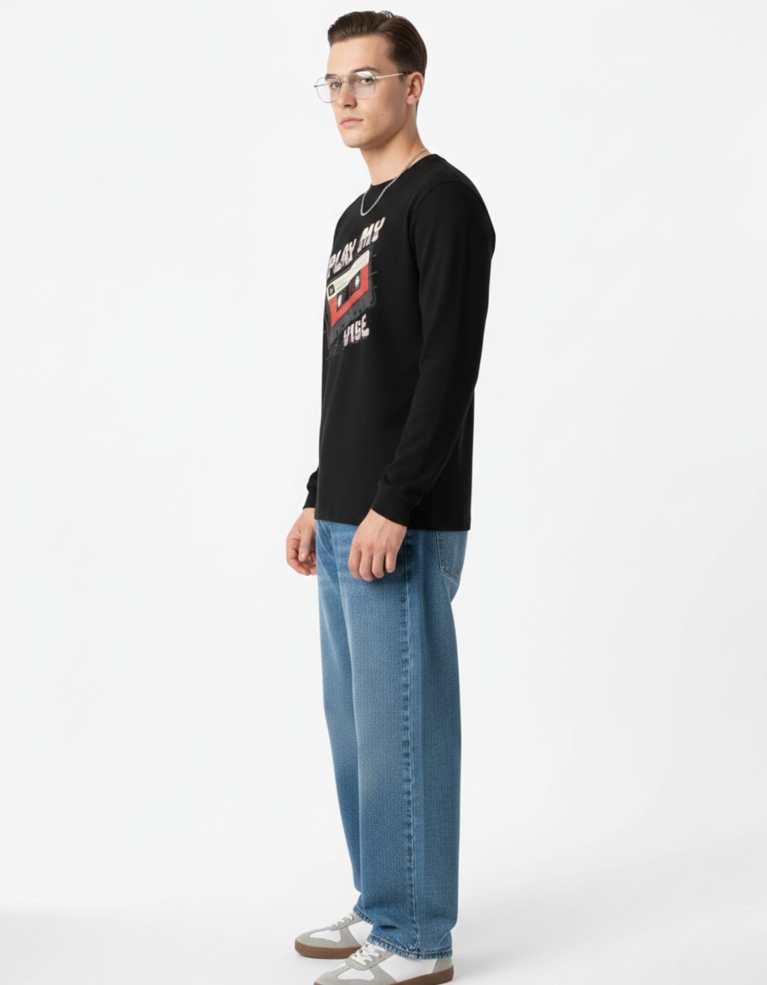 Man wearing a black long-sleeve shirt with a graphic design and blue jeans on a white background
