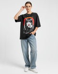 Woman wearing an oversized maroon graphic t-shirt with a vintage 'Beauty' winking girl print and baggy blue jeans.