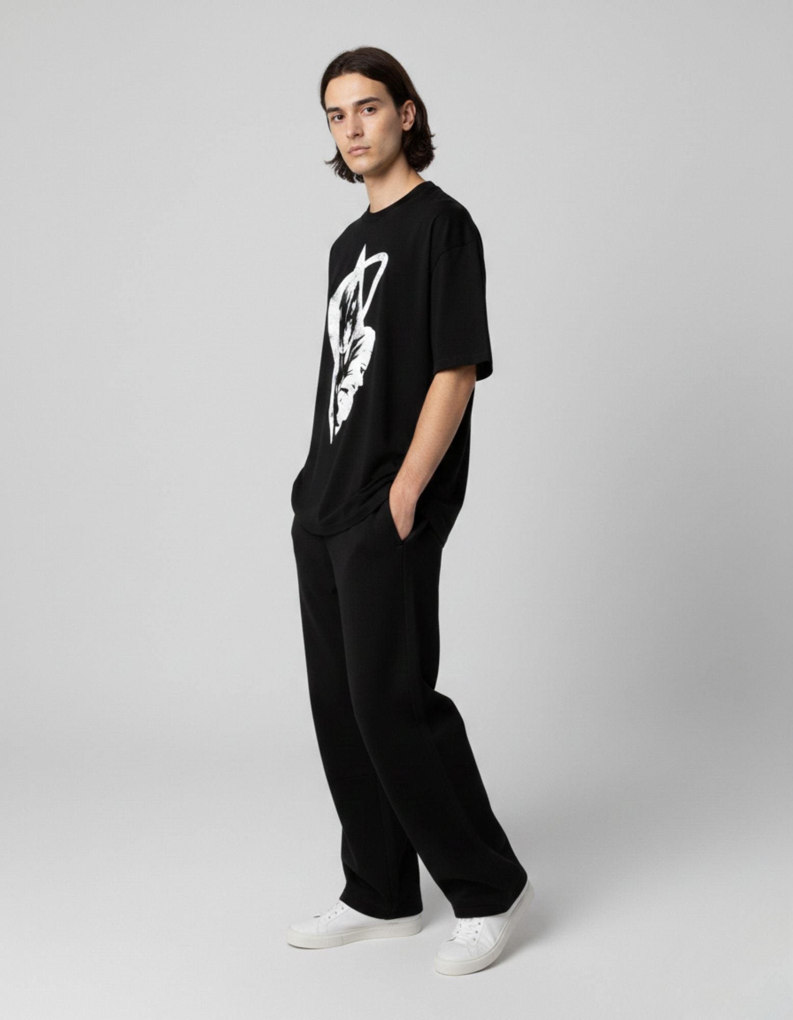 Side angle of a male model wearing a black graphic tee with anime print, showcasing the relaxed drop-shoulder fit.