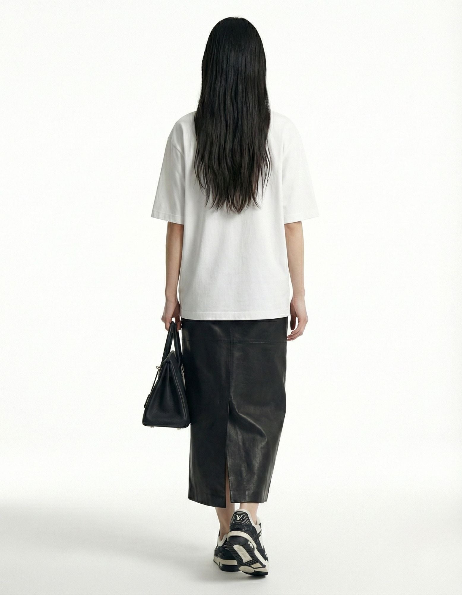 "Back view of a white oversized t-shirt on a female model, demonstrating the relaxed unisex fit."