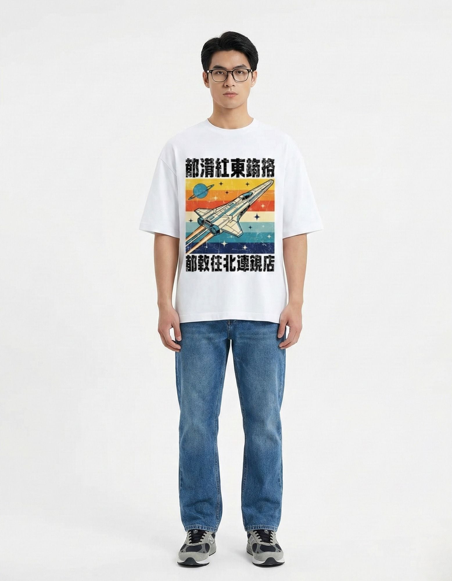 "Full length view of male model wearing a baggy white graphic tee with retro space illustration and blue jeans."