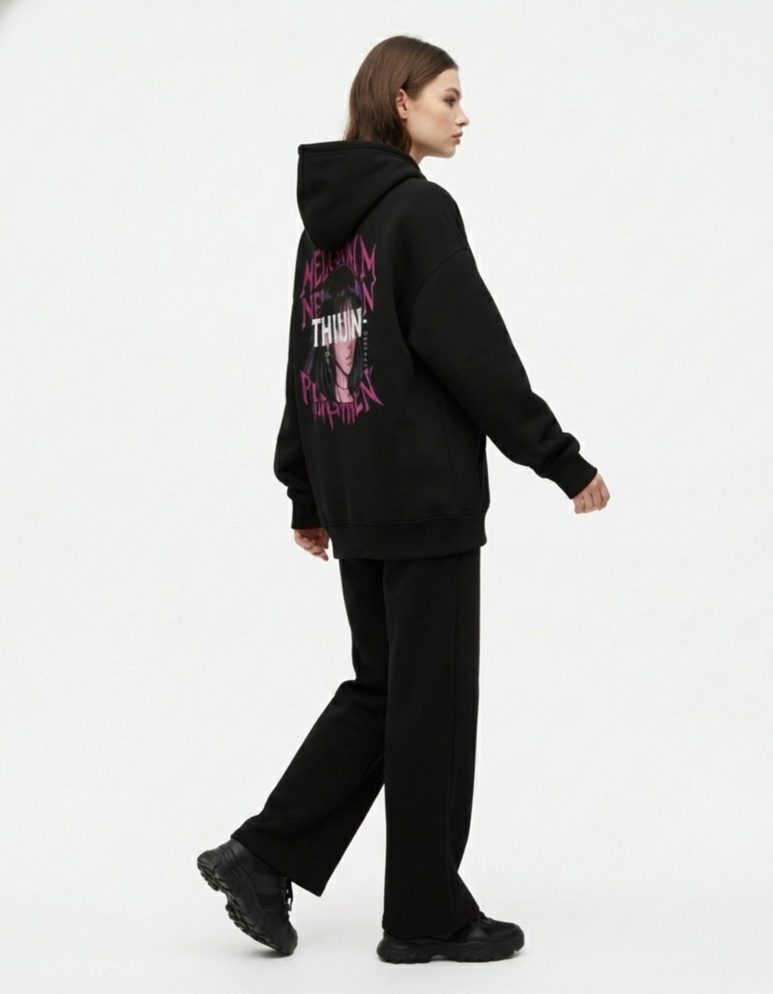 Side view of a model walking in a black aesthetic anime hoodie, showcasing the "THIUN-" manga girl design on the back.