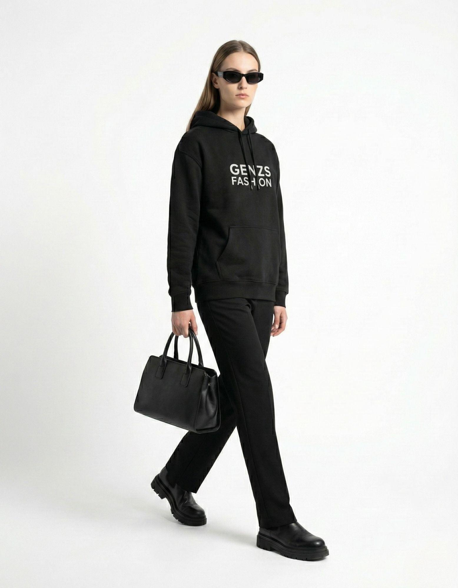 A woman walking in a premium black GENZs Fashion hoodie paired with black trousers and a handbag, showcasing Gen Z streetwear style.