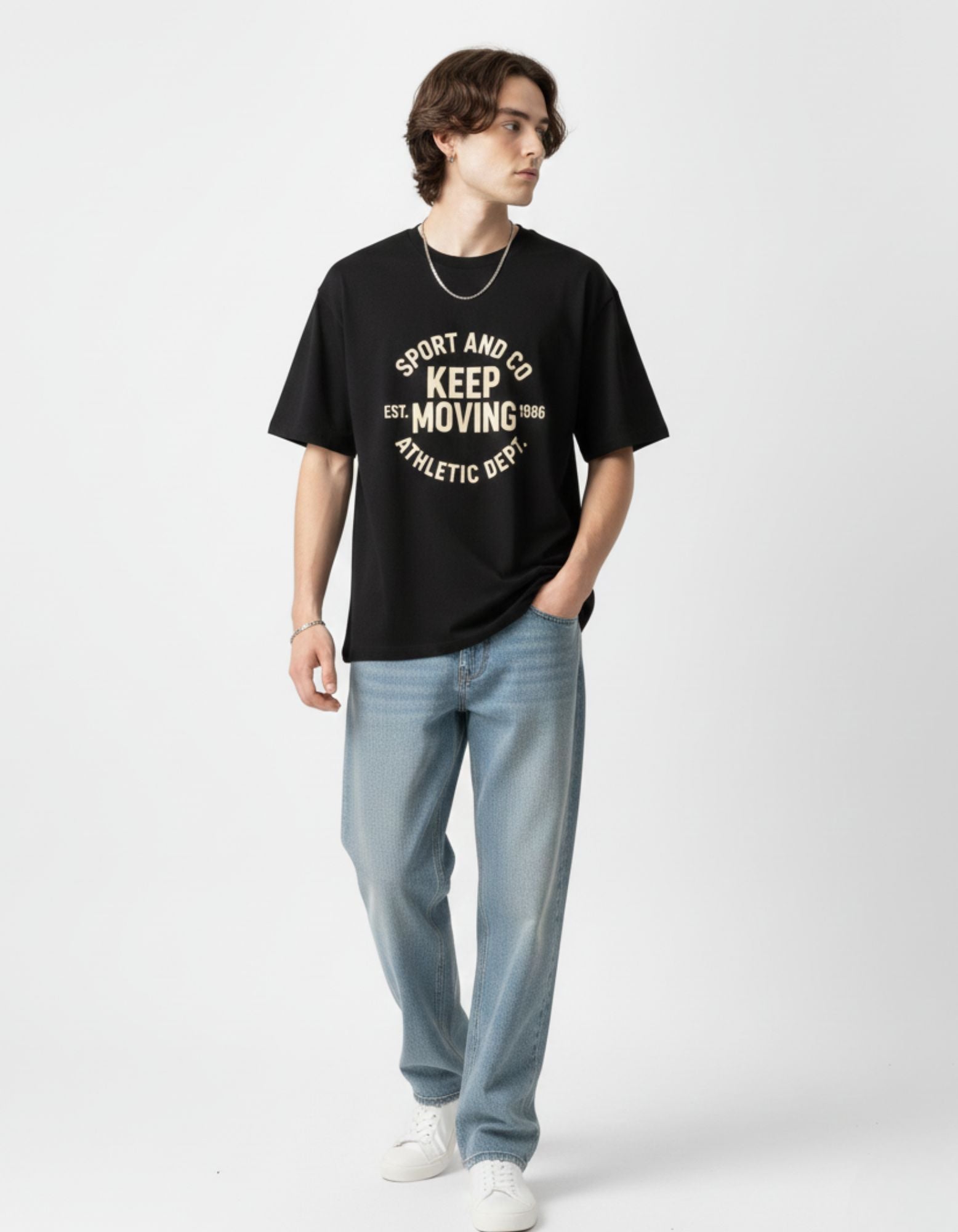 Front view of a black oversized graphic t-shirt for men featuring 'Keep Moving' athletic print, styled with blue jeans.