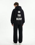 Male model wearing the "Do You Bleed?" graphic back print on a black oversized streetwear hoodie from GENZs Fashion.