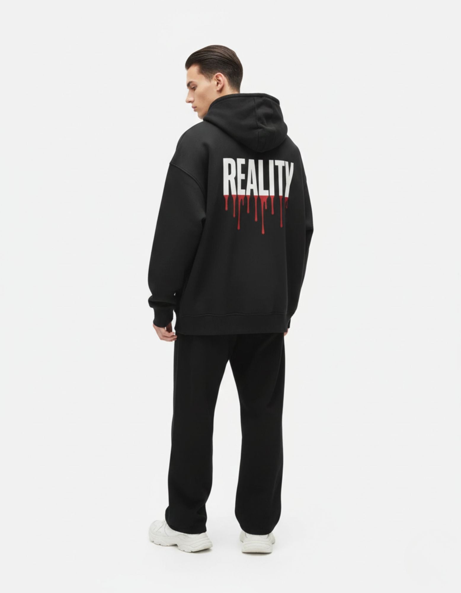 Back view of a male model wearing a premium black oversized hoodie from GENZs Fashion featuring a white 'REALITY' graphic with red drip effect.