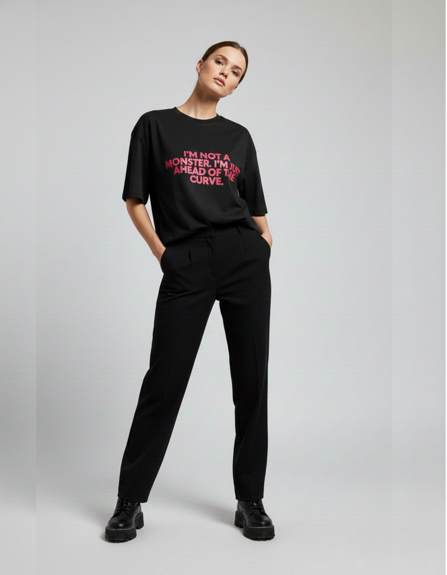 Black printed oversized tee for women with bold pink quote, styled with black trousers for urban Indian fashion.