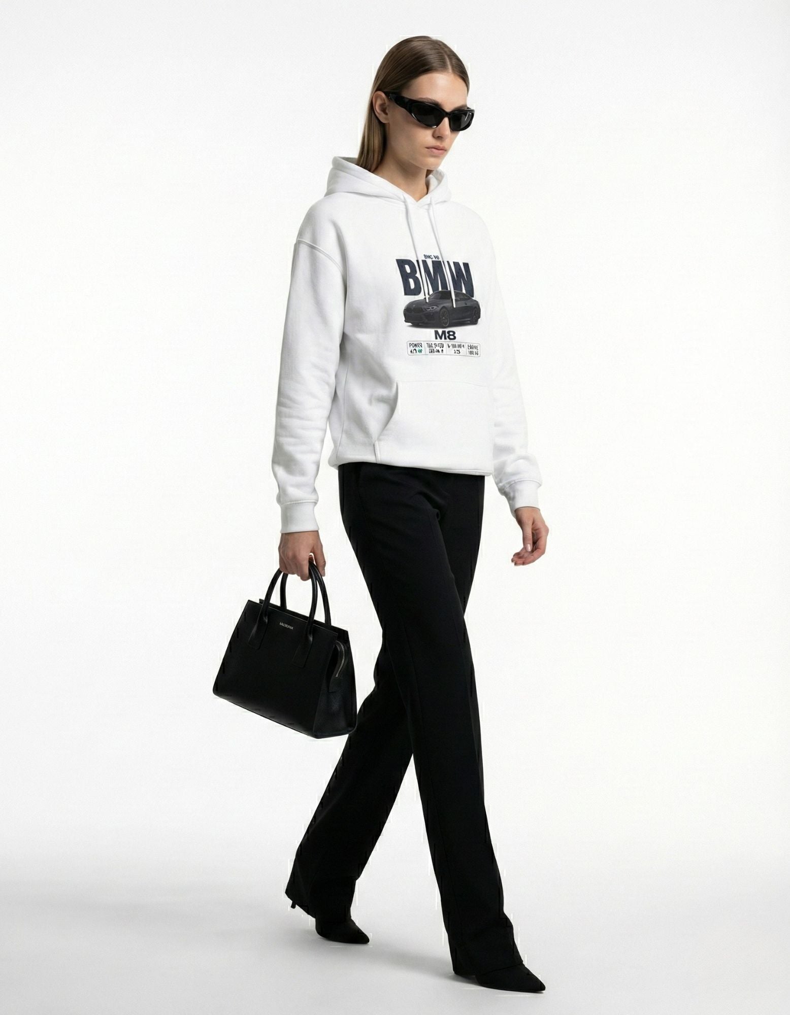 Female model styling a GENZs Fashion white BMW M8 hoodie with black trousers and sunglasses for a high-fashion car aesthetic.