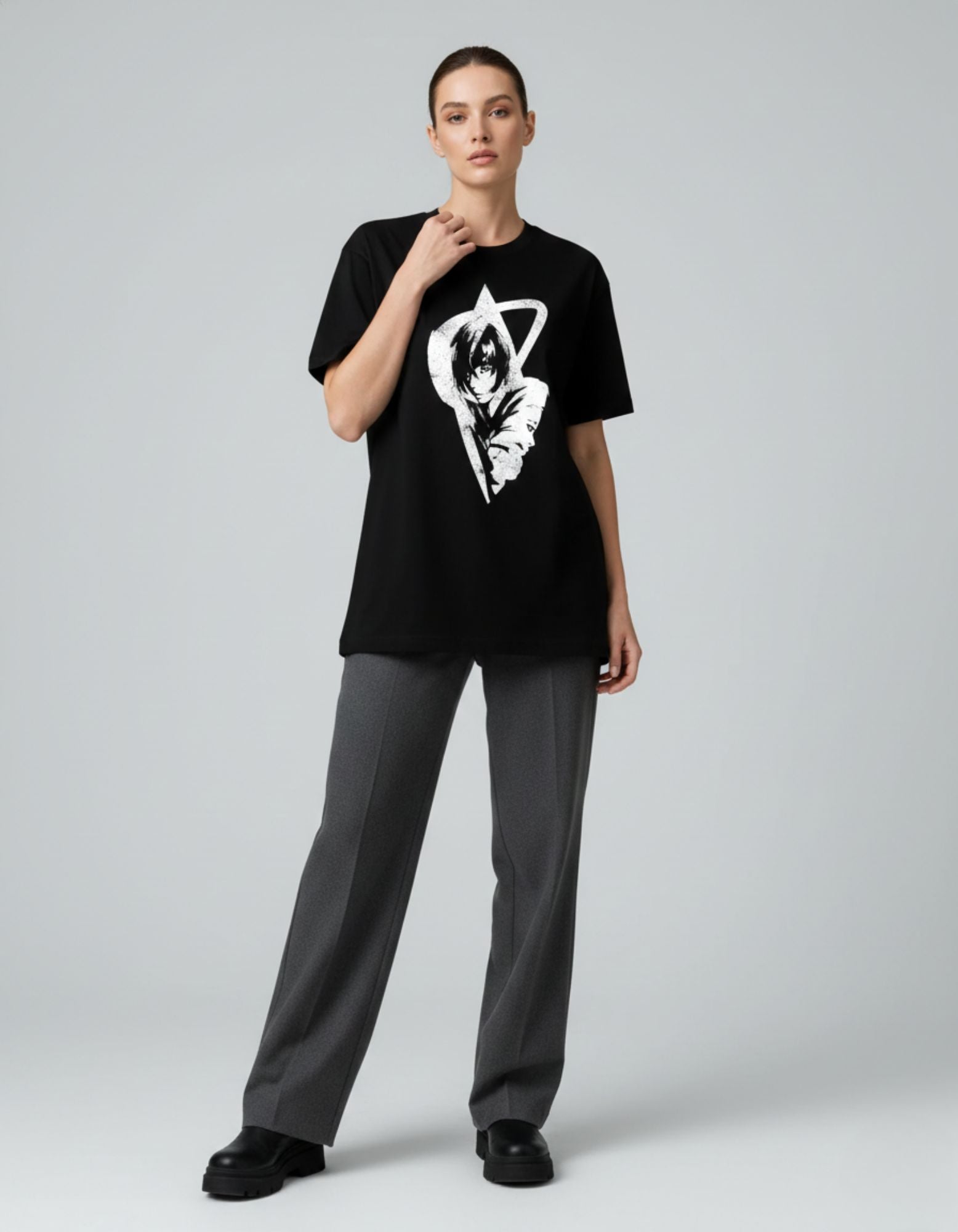 Fashion shot of a woman in a black graphic t-shirt with anime design, showing a relaxed urban aesthetic.