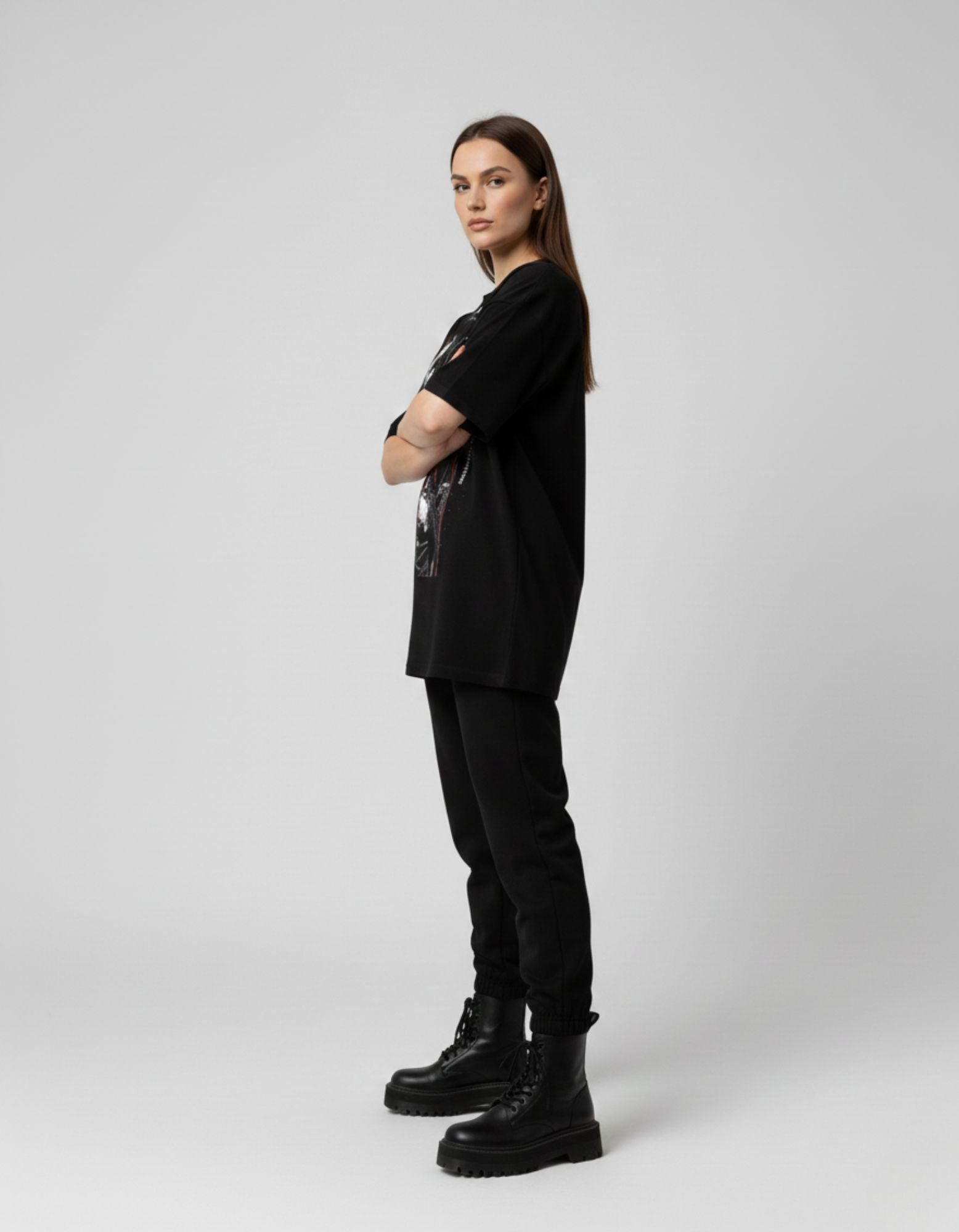 Side view of a woman wearing a black oversized graphic tee, highlighting the versatile unisex styling of the product.
