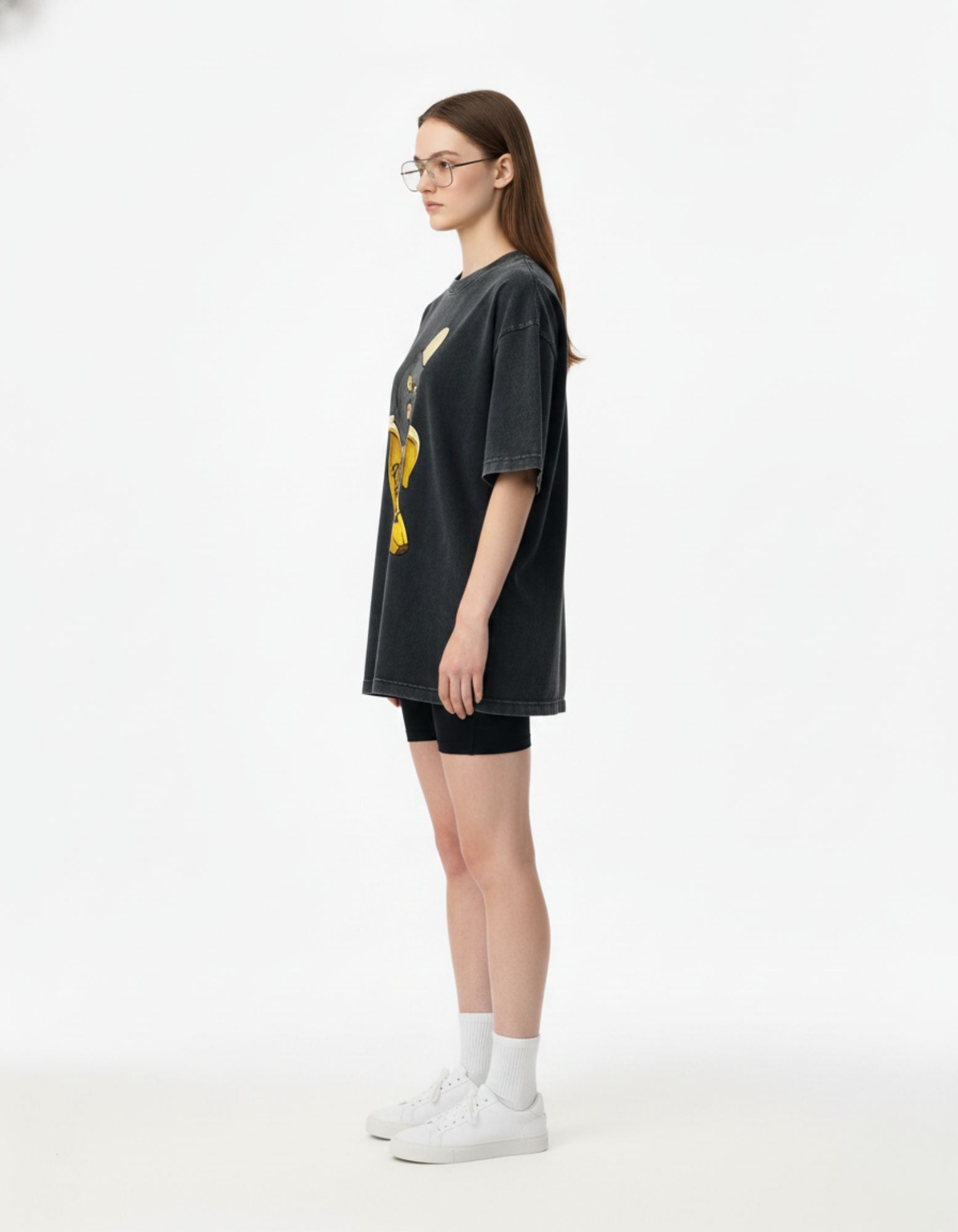 Side view of a charcoal oversized streetwear t-shirt on a female model highlighting the baggy, unisex aesthetic.