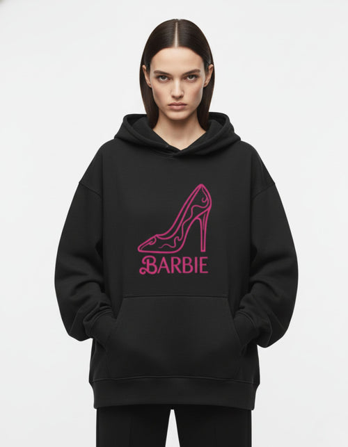 Close-up of the pink high-heel and Barbie logo printed on a premium heavy-weight black oversized hoodie.