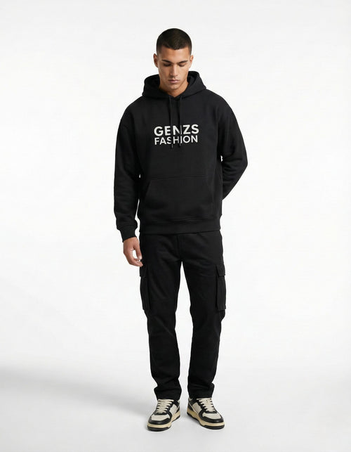 A man wearing a black GENZs Fashion hoodie with white text logo and black cargo pants, a complete urban streetwear look.