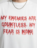 Close-up of GENZs Fashion white oversized tee featuring red dripping 'My enemies are countless' typography.