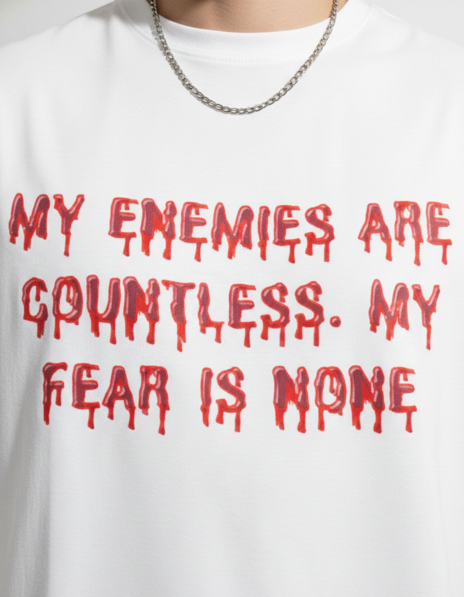 Close-up of GENZs Fashion white oversized tee featuring red dripping 'My enemies are countless' typography.