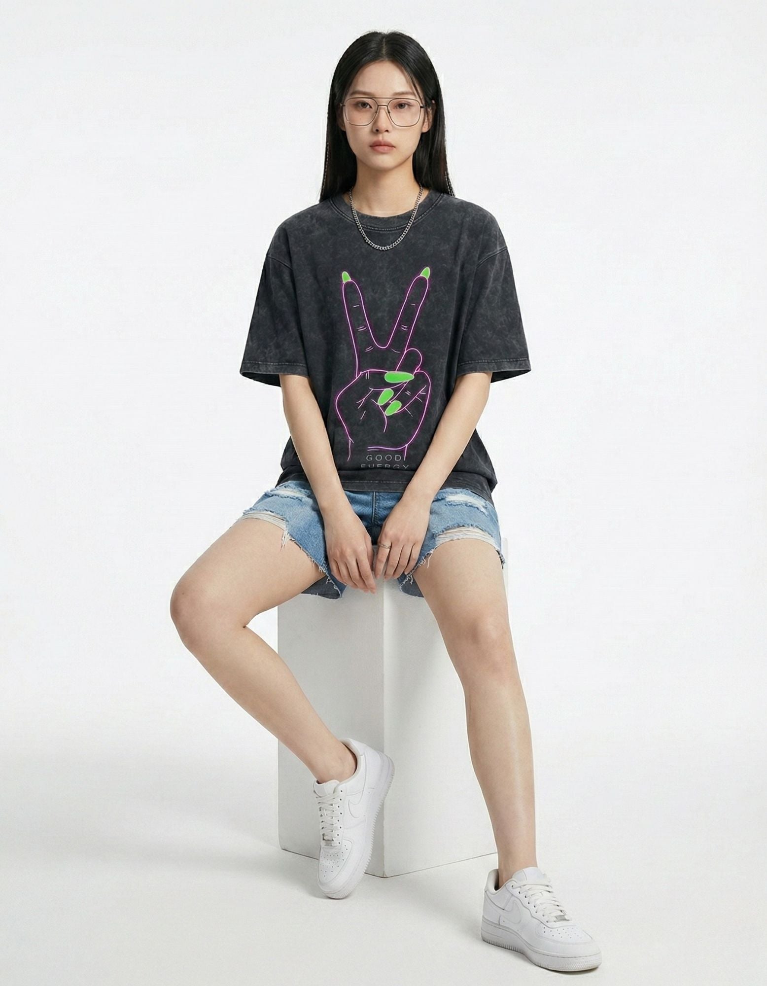 "Model wearing an oversized charcoal graphic tee with denim shorts and white sneakers, showcasing a Gen Z streetwear aesthetic."