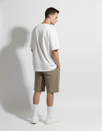 Back view of white oversized heavyweight cotton tee by GENZs Fashion, styled with casual beige streetwear shorts.
