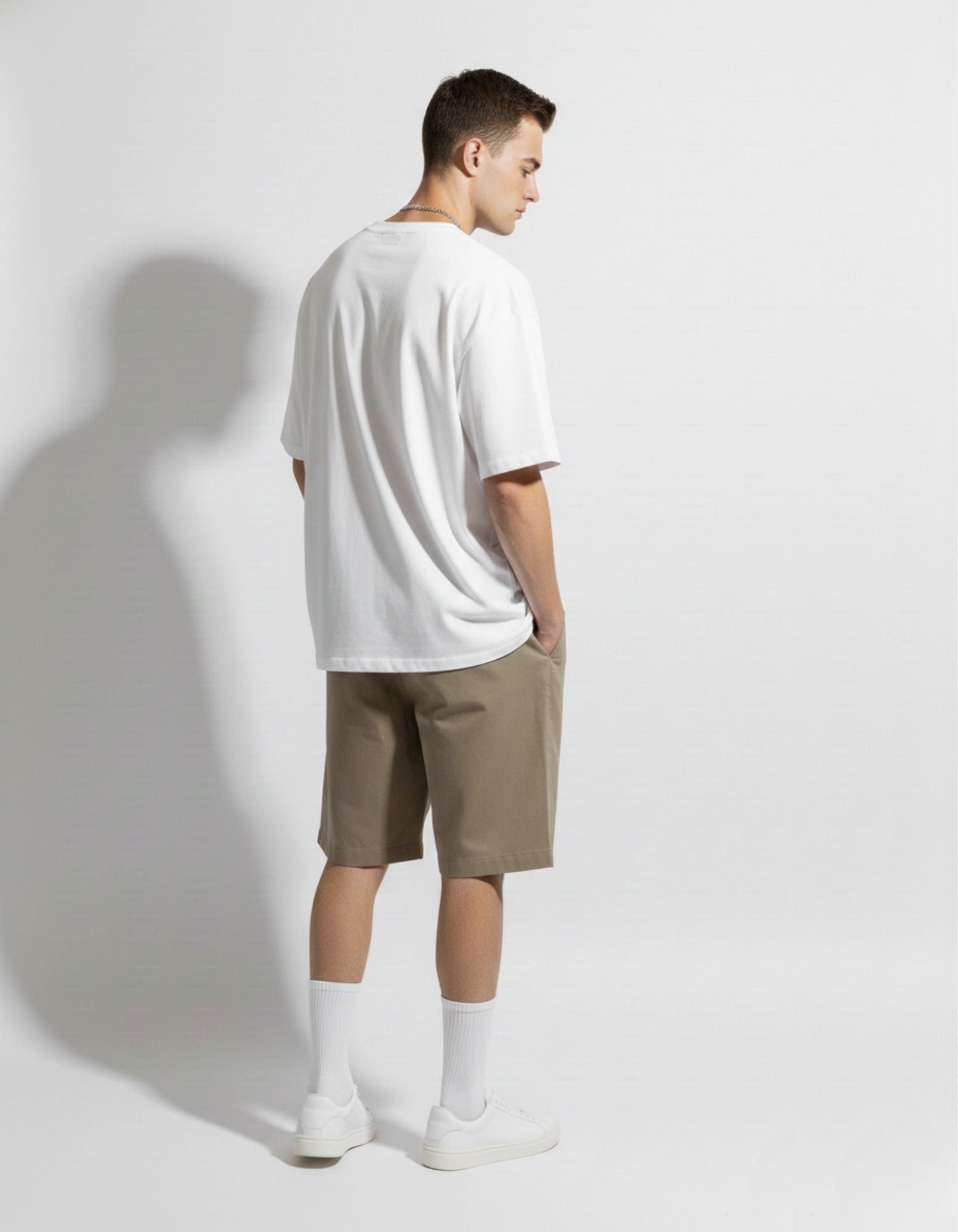 Back view of white oversized heavyweight cotton tee by GENZs Fashion, styled with casual beige streetwear shorts.