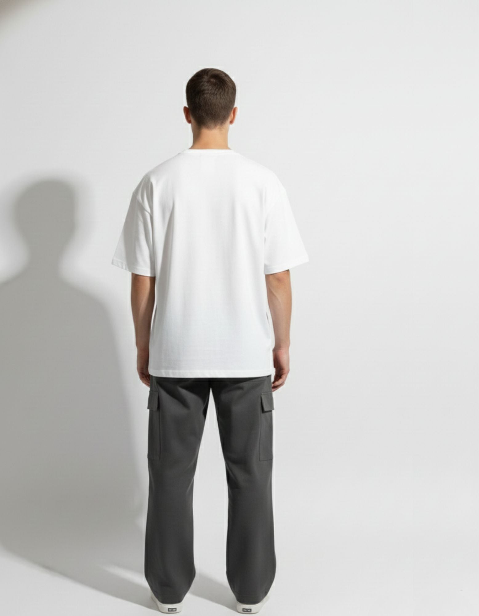 Back view of GENZs Fashion white drop shoulder oversized tee and grey utility cargo pants, showing the signature baggy fit silhouette.
