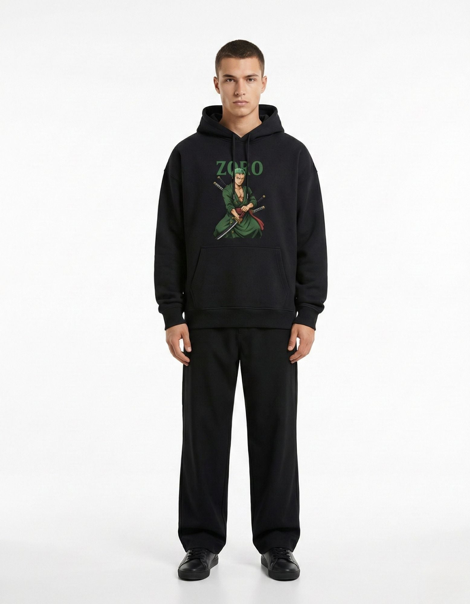 Full front view of a male model wearing a black One Piece themed hoodie with a Roronoa Zoro graphic and black trousers.