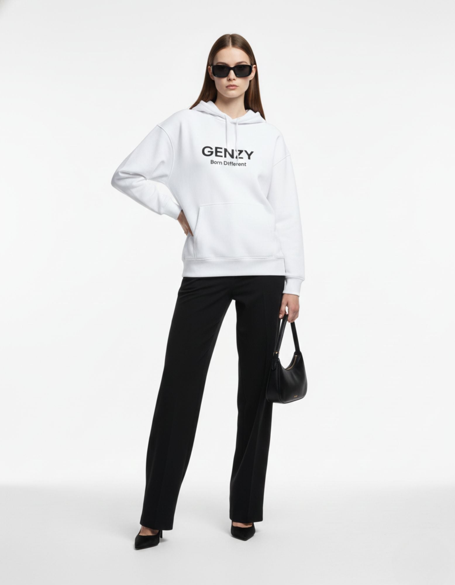 Full front view of a female model in a white GENZY Born Different hoodie, demonstrating a minimalist streetwear look with a black handbag.