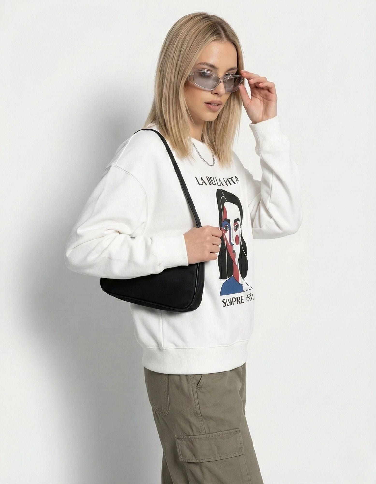 Female model posing in a 'La Bella Vita' minimalist art sweatshirt, showcasing a trendy 2025 Gen Z urban outfit.