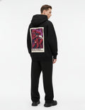 Male model wearing a black GENZs Fashion hoodie with a large Madara Uchiha "Wake Up To Reality" graphic on the back.