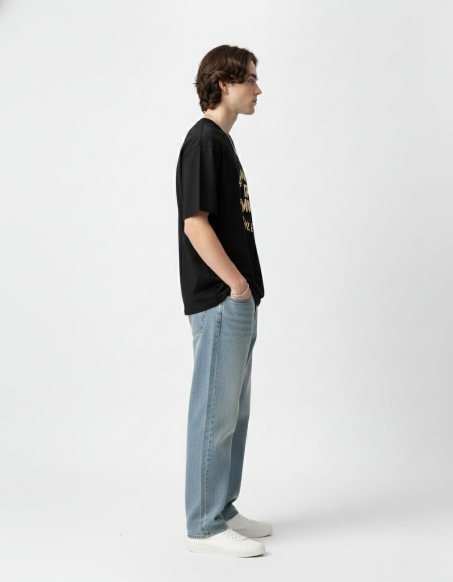 Side profile of a black drop-shoulder streetwear t-shirt showing the relaxed fit and cotton fabric quality.
