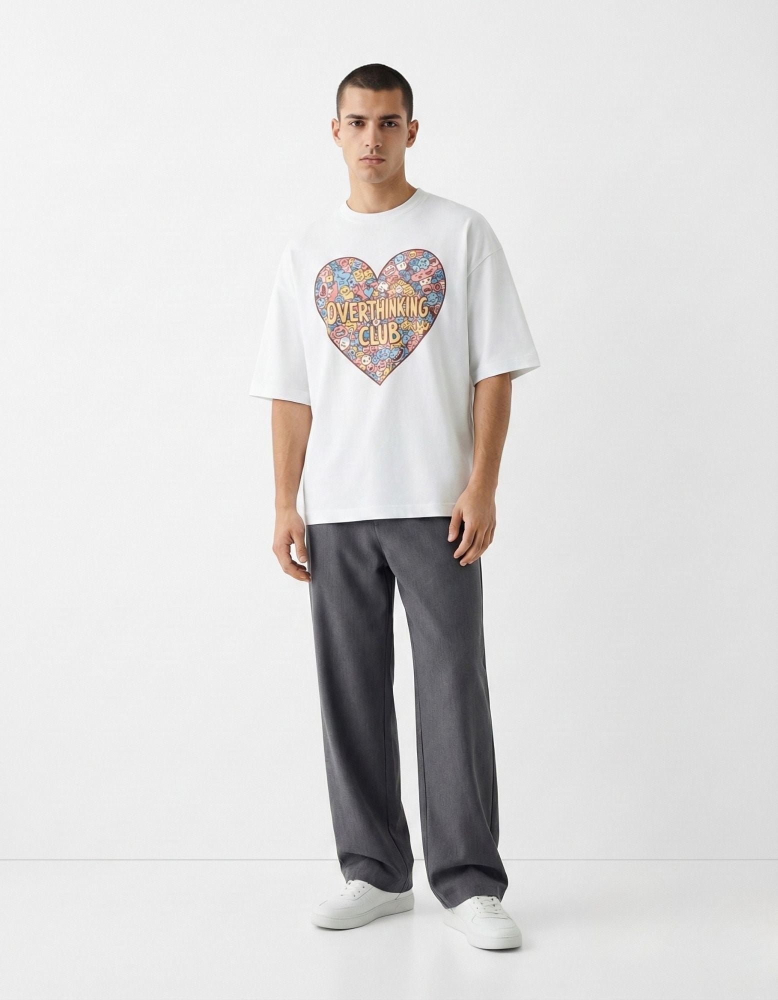 Male model in a GENZs Fashion white oversized t-shirt featuring a heart-shaped doodle graphic with "Overthinking Club" text.
