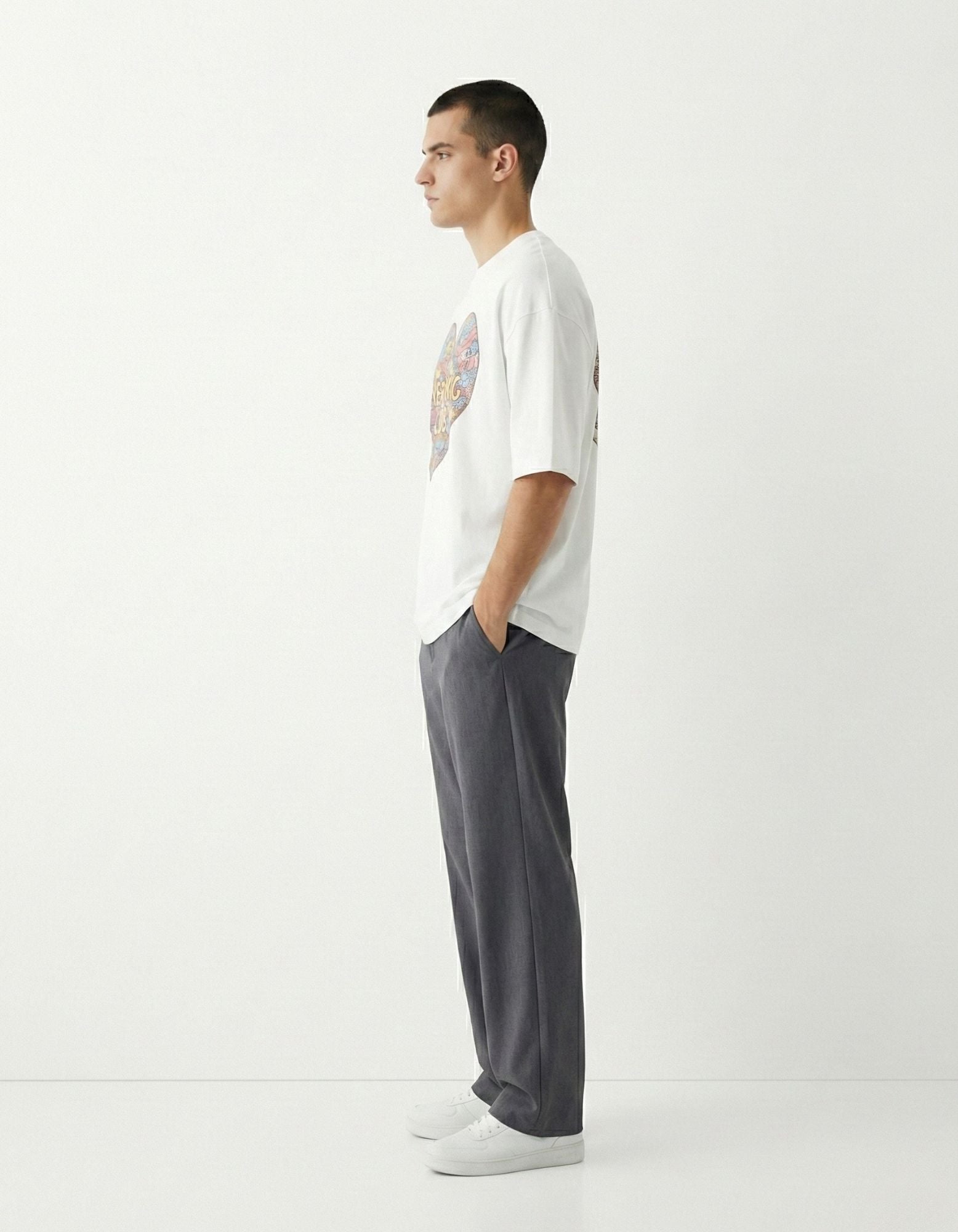 Side view of a male model in a GENZs Fashion oversized white tee, highlighting the loose sleeves and heavy-weight cotton drape.
