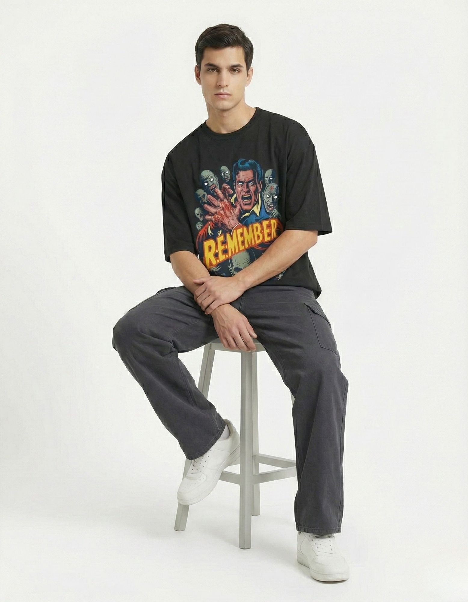 Male model sitting on a stool wearing a black GENZs Fashion oversized graphic tee, emphasizing the relaxed and versatile streetwear style.