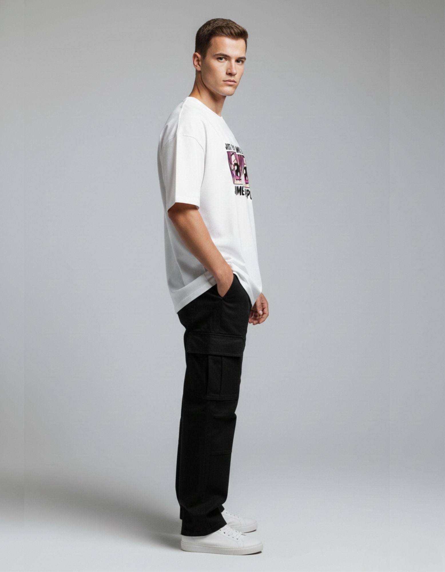 Side view of a male model styling an anime oversized tee with black multi-pocket cargo pants, streetwear trend India.
