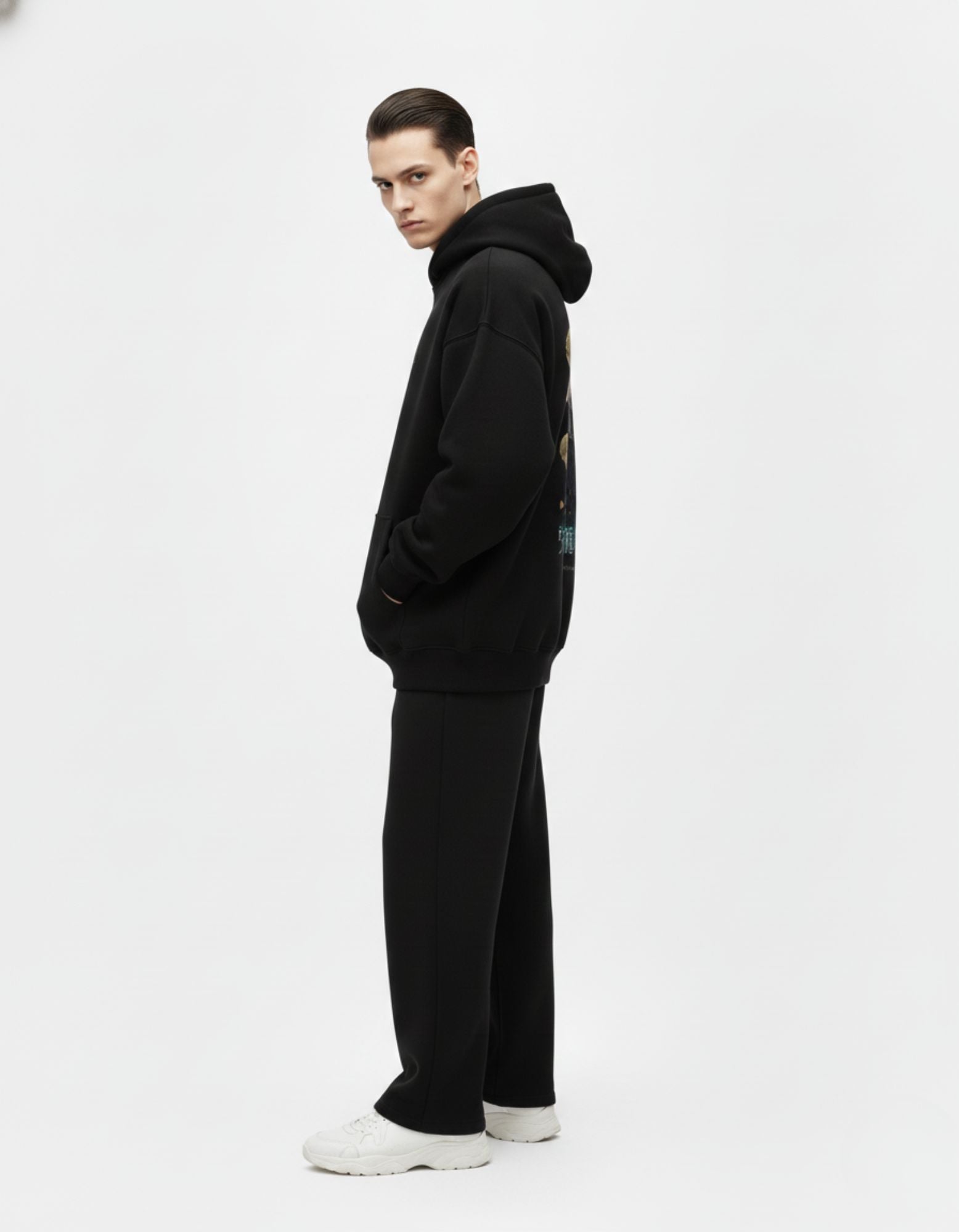 Side view of a male model wearing a premium black heavyweight hoodie, highlighting the relaxed streetwear fit.