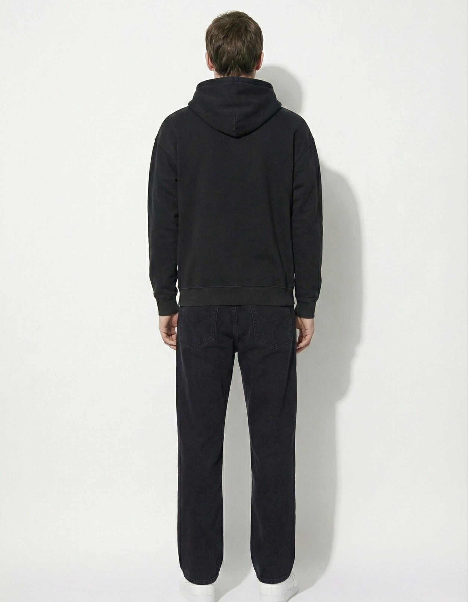 Back view of a male model wearing a premium black oversized hoodie, highlighting the high-quality fabric texture.