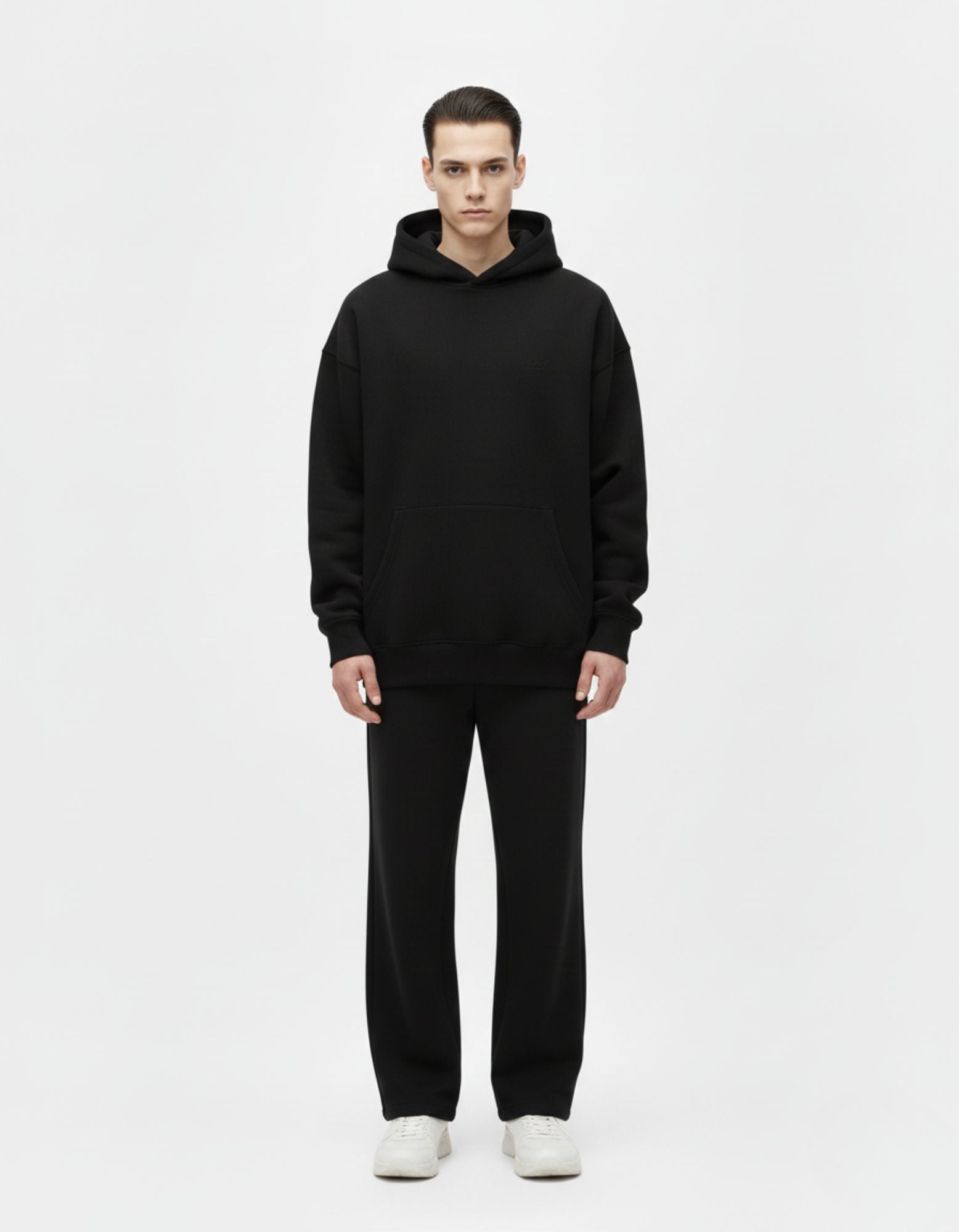 Front standing view of a male model wearing a high-quality black streetwear hoodie with a premium finish.