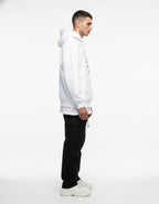 Side profile of a male model wearing a white streetwear hoodie with a graphic print, highlighting the drop-shoulder oversized fit.