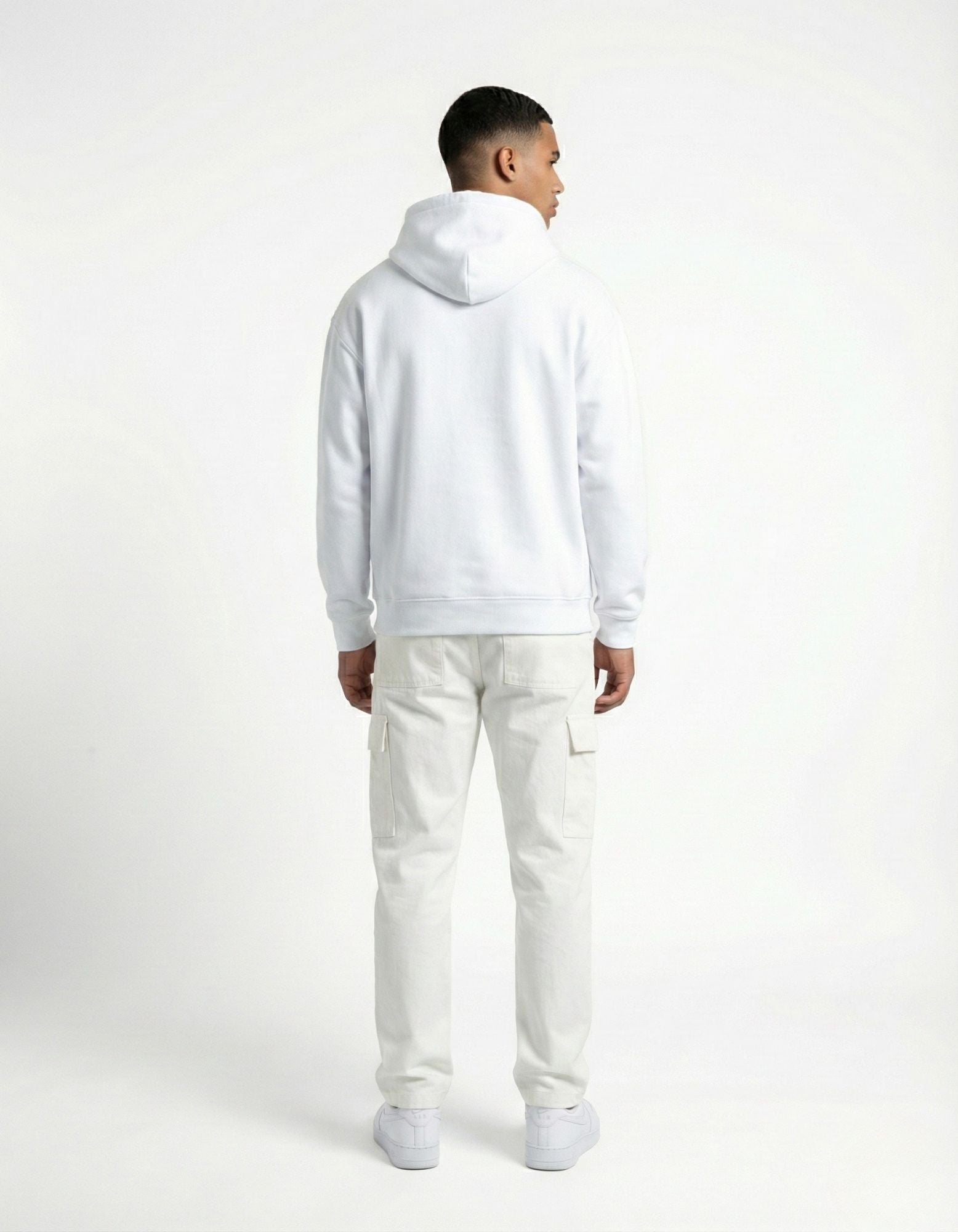 Side view of a woman walking in a white minimalist hoodie and black sunglasses.