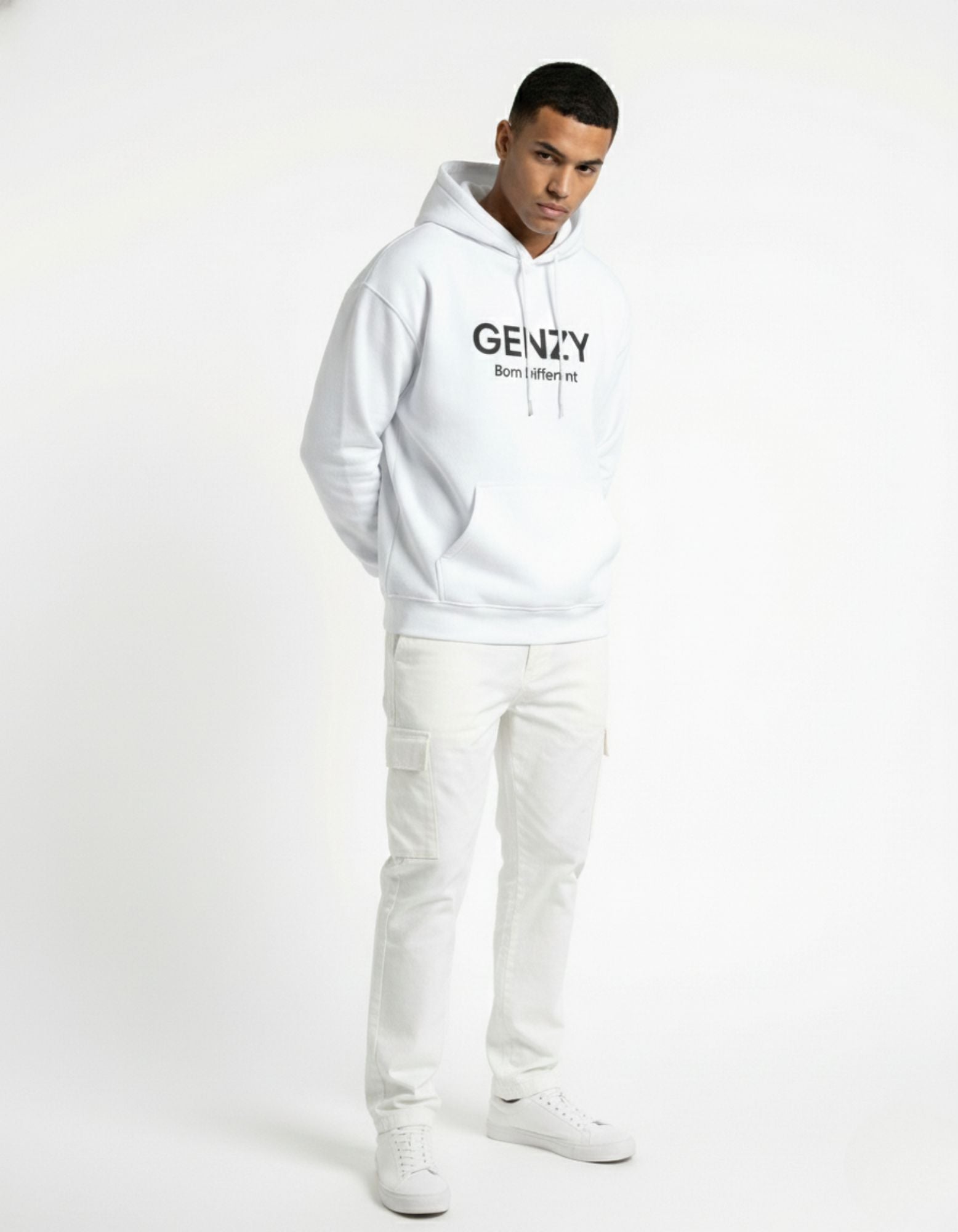 Male model wearing a white GENZY Born Different oversized hoodie paired with white cargo pants for a monochromatic streetwear aesthetic.