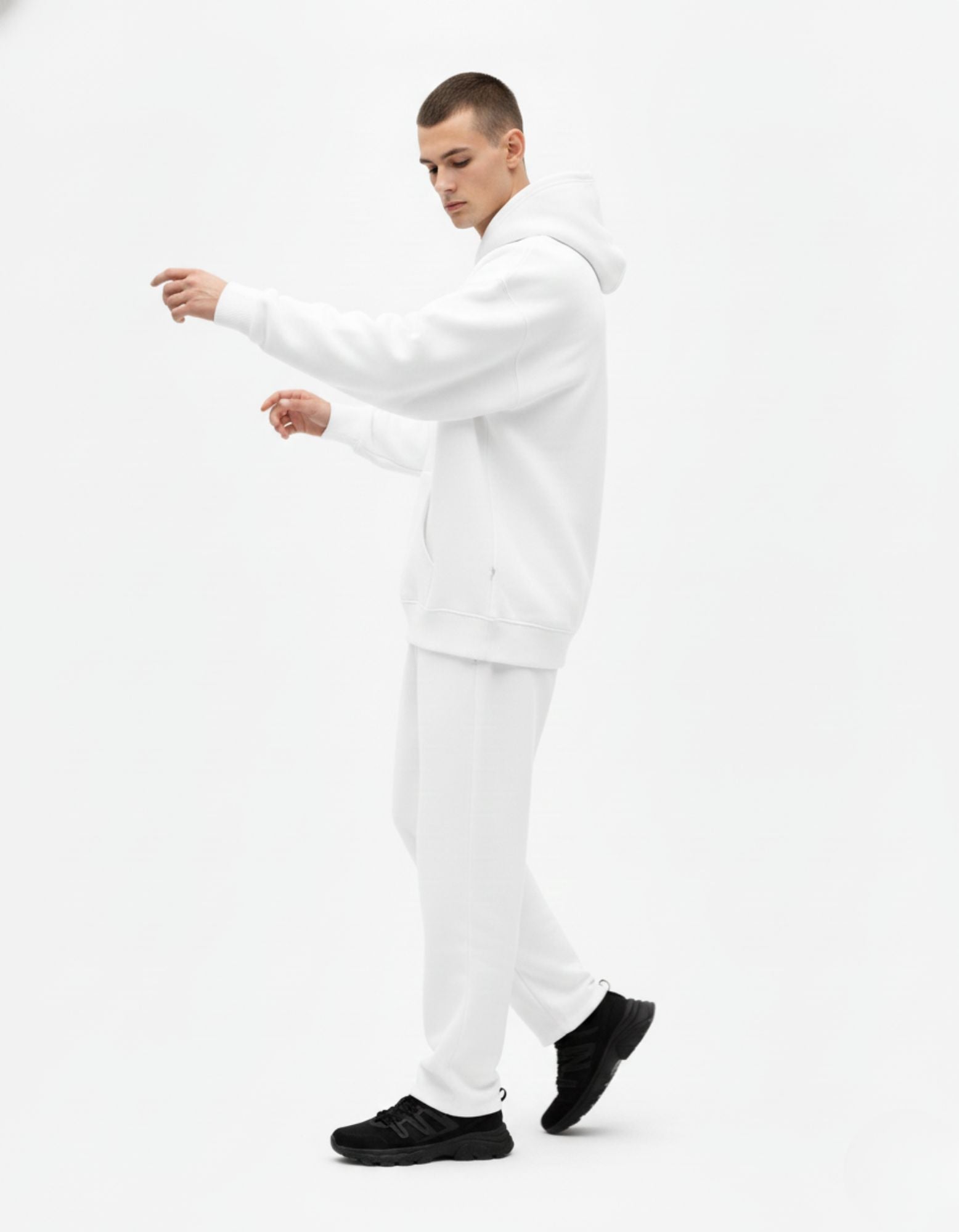 Side view of a male model wearing a premium white oversized hoodie and matching joggers set from GENZs Fashion streetwear collection.