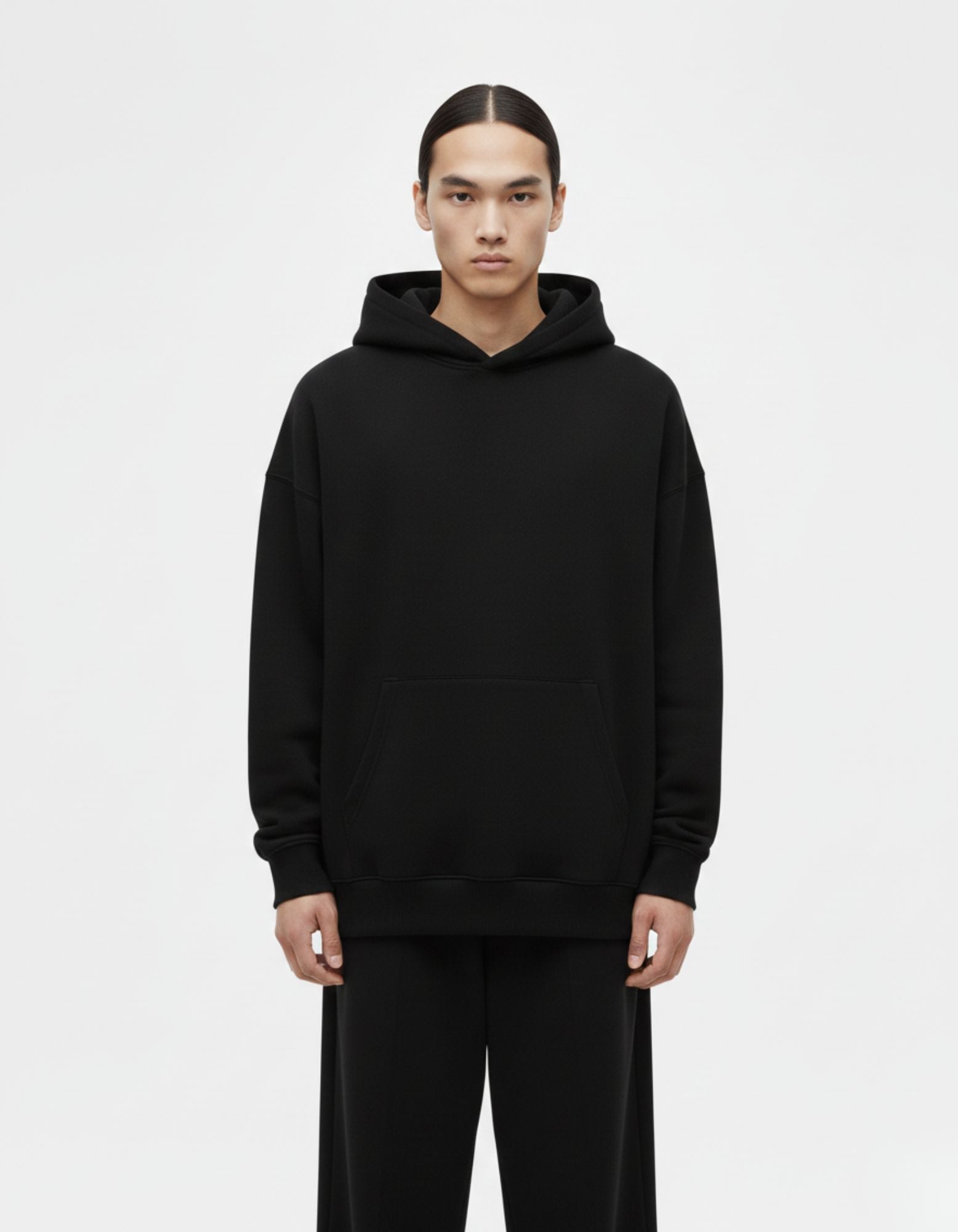 Front view of a minimalist black oversized hoodie for men, made with heavyweight cotton for a clean streetwear look.