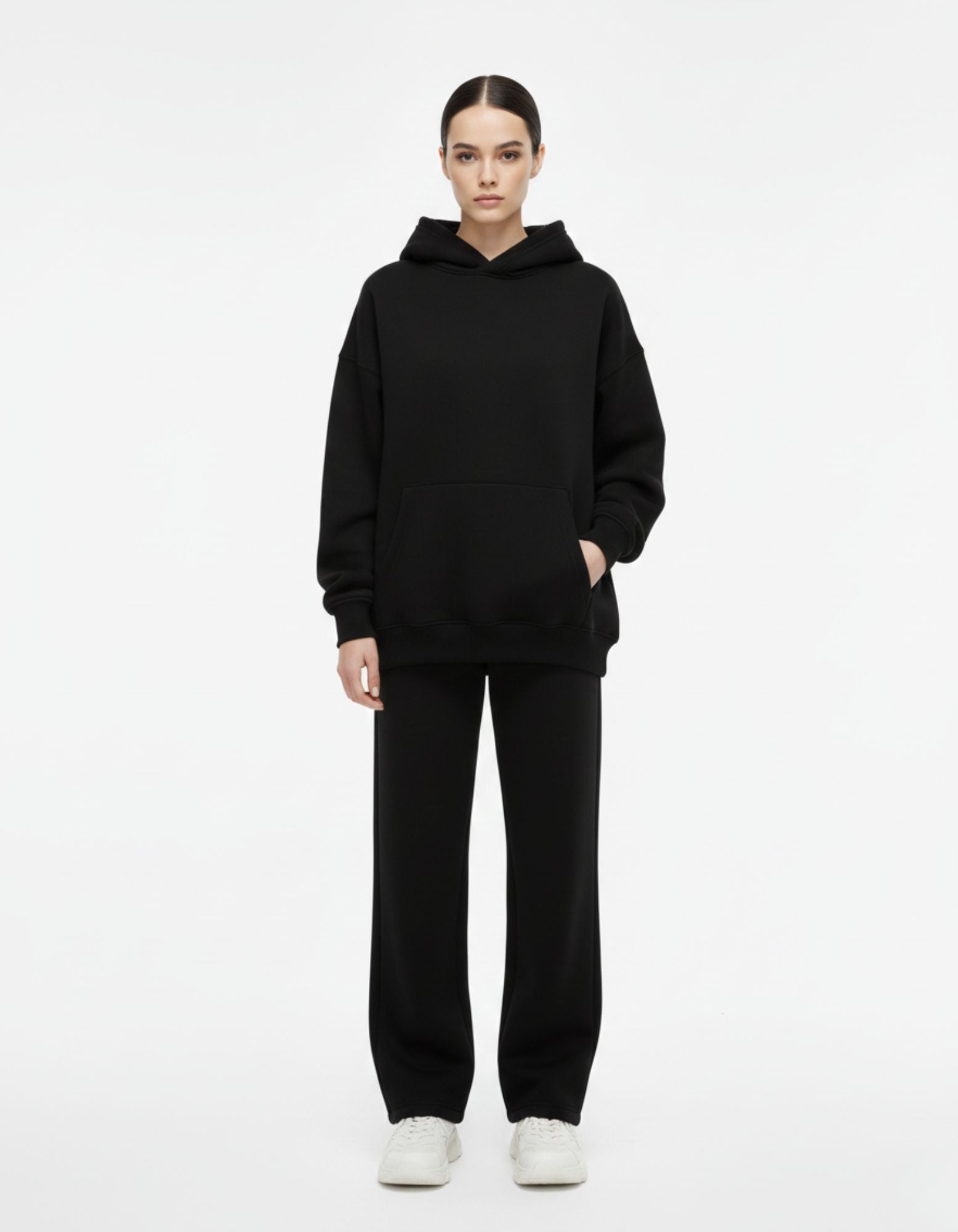 Front view of a female model in a plain black oversized hoodie with a kangaroo pocket, showing the clean front design.