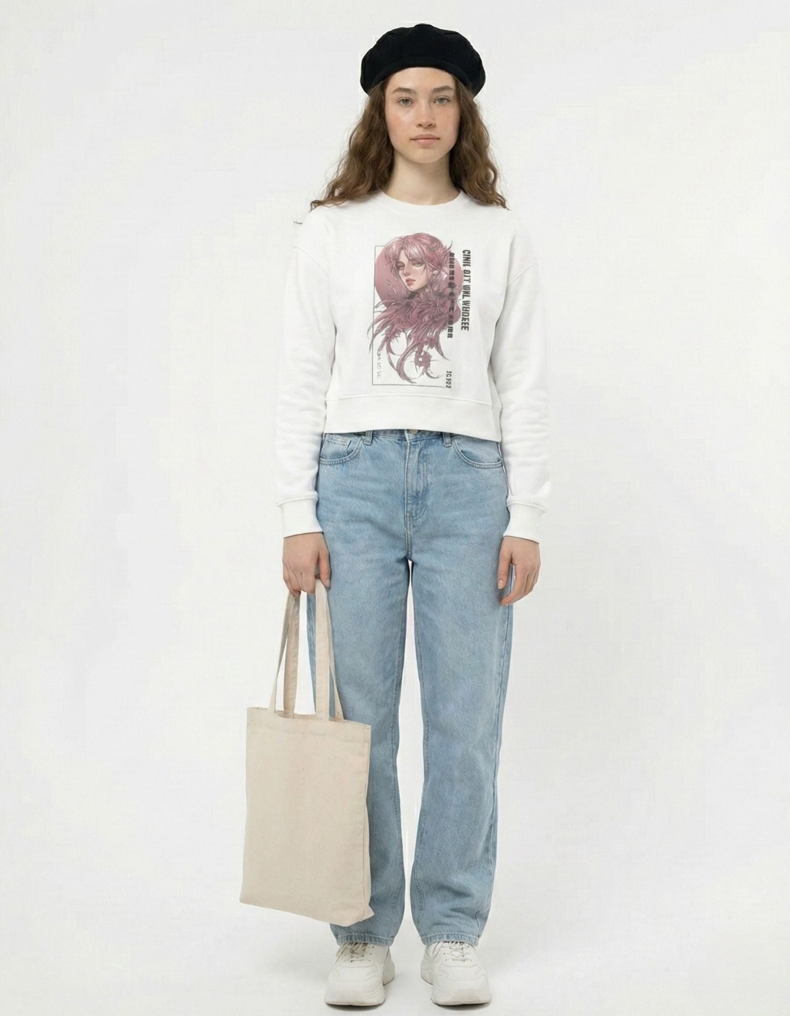 Full standing view of a female model in a white graphic sweatshirt and light blue jeans, accessorized with a black beret and cream tote bag.