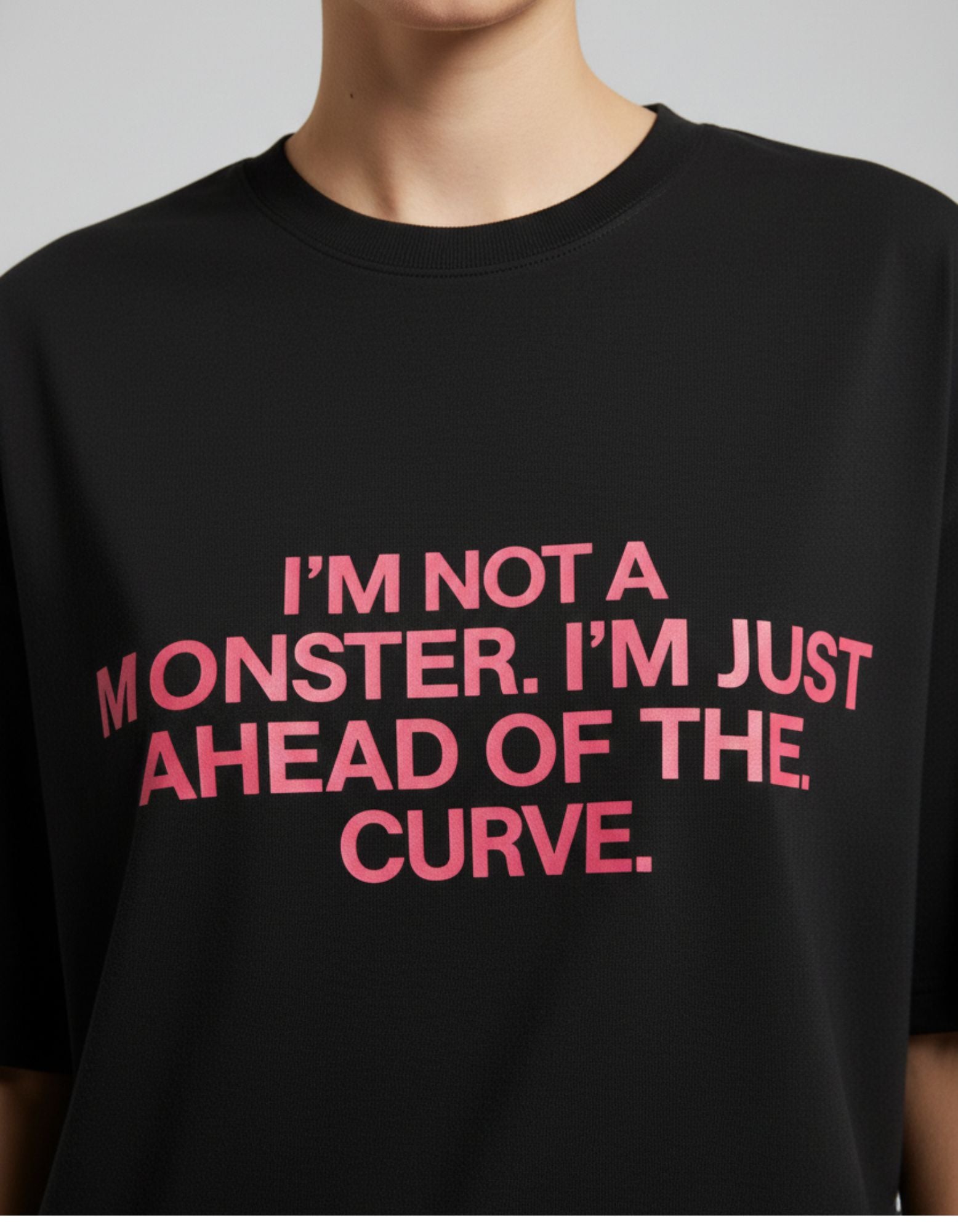 Close-up of pink "I'M NOT A MONSTER" quote on black oversized cotton t-shirt, showing print quality and fabric.