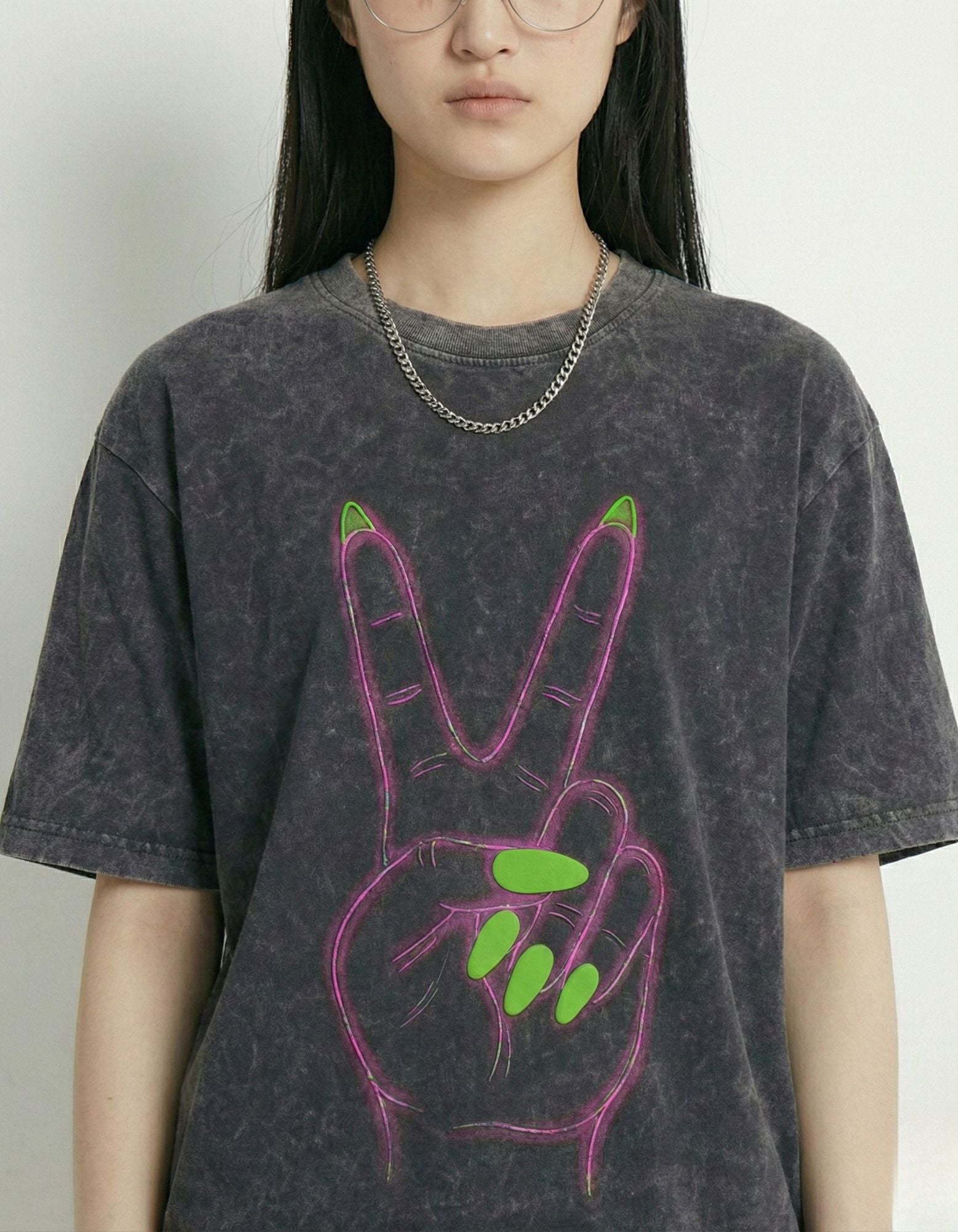 "Close-up detail of the neon pink peace sign graphic with green nails and 'Good Energy' typography on a grey acid wash cotton tee."