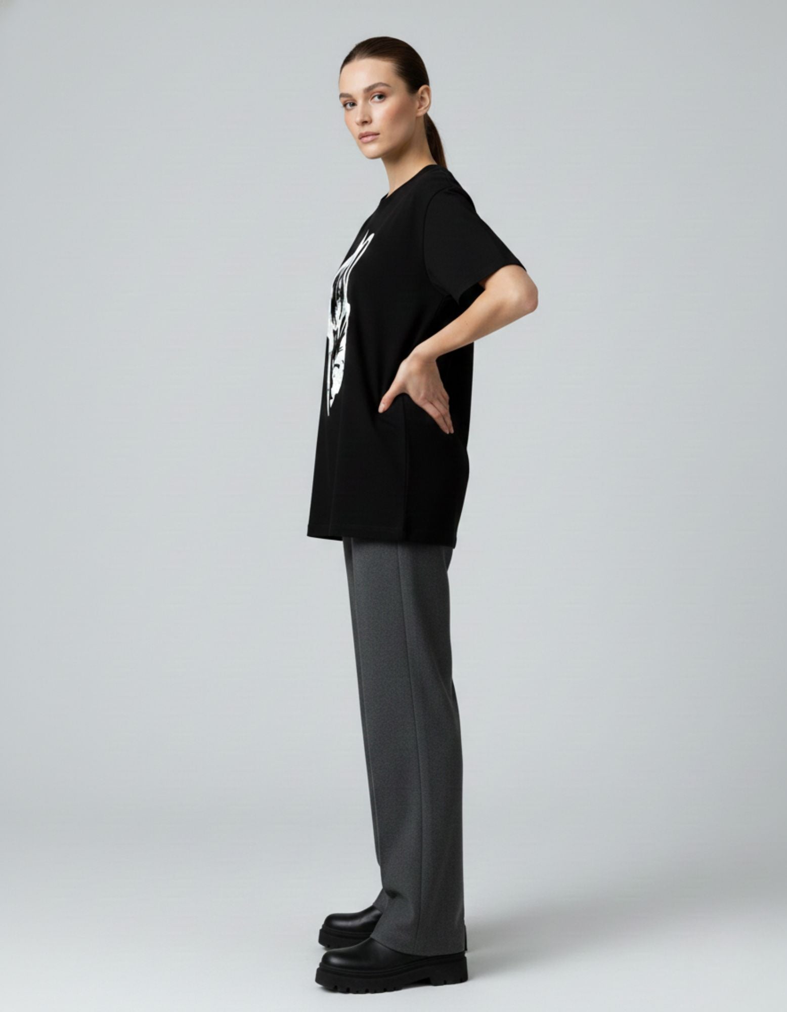 Side view of a female model wearing an oversized black anime graphic t-shirt by GENZs Fashion.