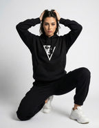 Female model kneeling in an oversized black hoodie with a minimalist aesthetic graphic, ideal for Gen Z streetwear style.