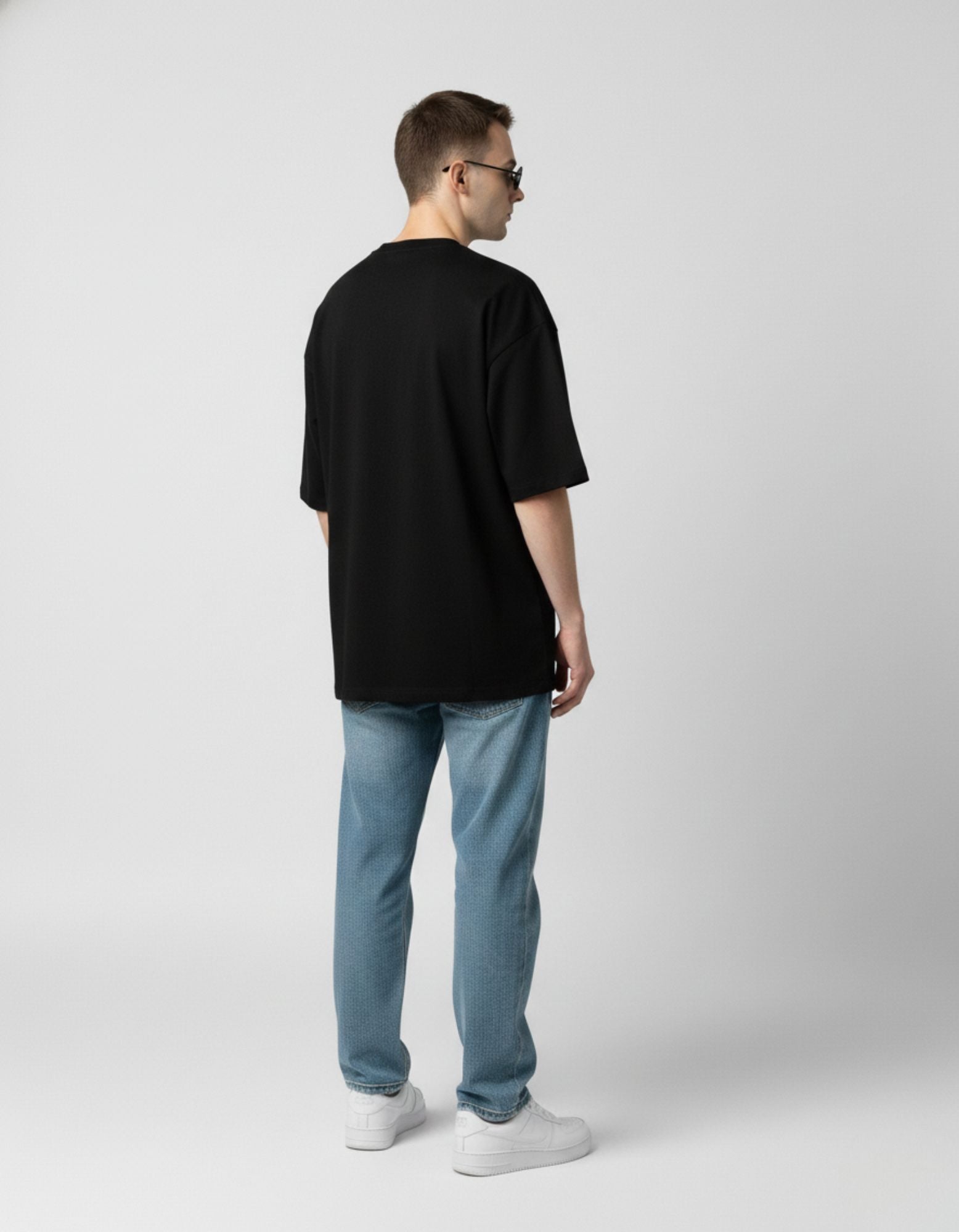 Back view of an oversized black heavyweight cotton t-shirt showing the relaxed drop-shoulder streetwear fit.